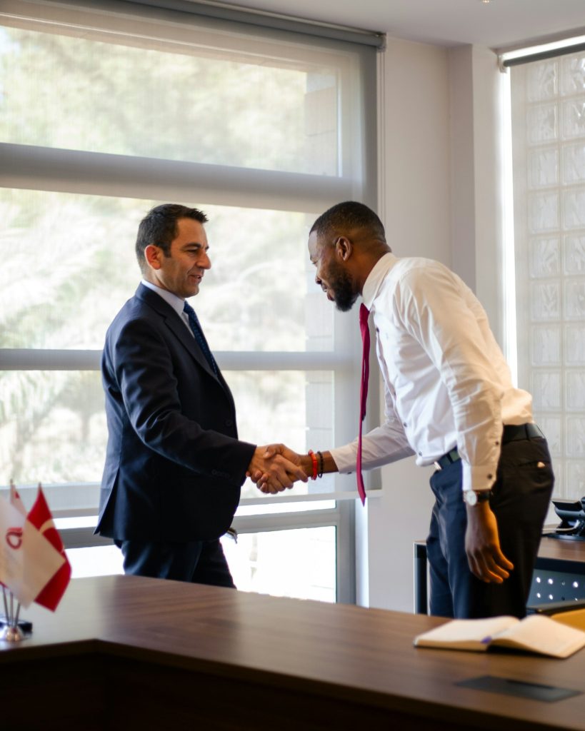 Two business people shaking hands across a desk, representing trust in E-E-A-T
