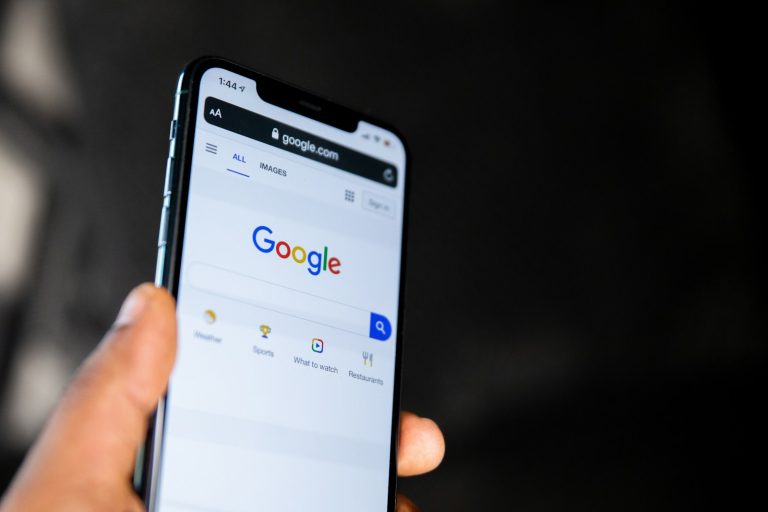 Hand holding a smartphone showing Google search, illustrating SEO vs SEM for Malaysian businesses